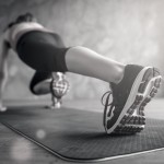 Close up of sportswoman`s sneakers. She is training in sunny room on the mat, weraing modern sportswear and special shoes for doing sports
