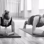 Front view of two sporty fit and slim middle aged women doing planking exercise indoors together with a natural light in modern interior sport studio hall or yoga class. Front view of two sporty fit and slim middle aged women doing planking exercise indoors together with a natural light in modern interior sport studio hall or yoga class.